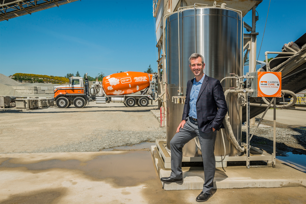 CEO of CarbonCure stands in front of concrete mixer truck and valve box