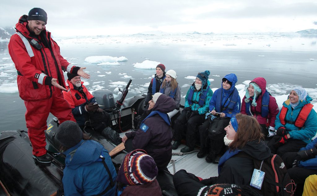 A Student on Ice teacher talks to students in a small boat surrounded by ice