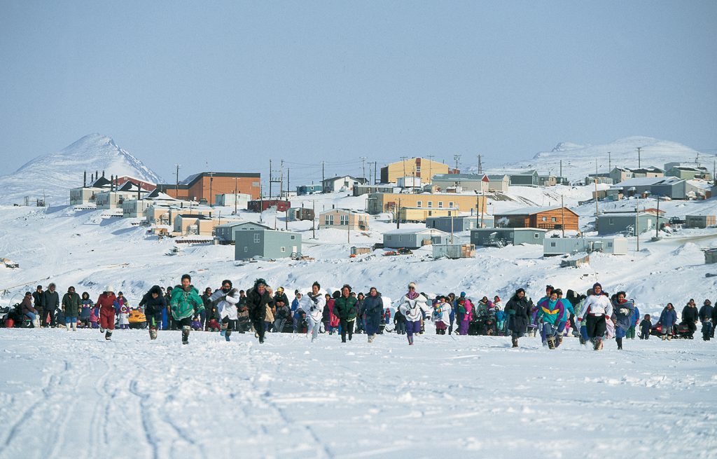 Women in Nunavut running across a snow-covered field towards the camera