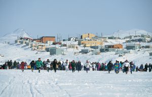Women in Nunavut running across a snow-covered field towards the camera