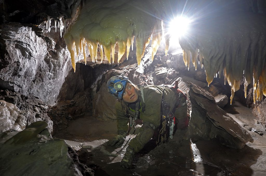 Kathleen Graham crawls beneath a curtain of stalactites inside Raspberry Rising cave