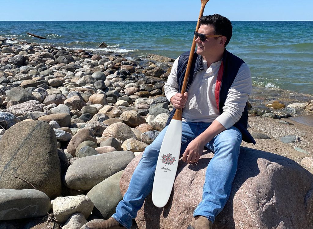 Patrick hunter sits with artisan canoe paddle