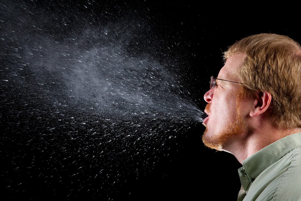 Man sneezes and expels droplets into air