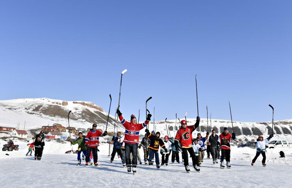 Mark Napier (left) and Lanny McDonald play hockey on the Arctic Ocean with youth from Arctic Bay. (Photo: Michelle Valberg)