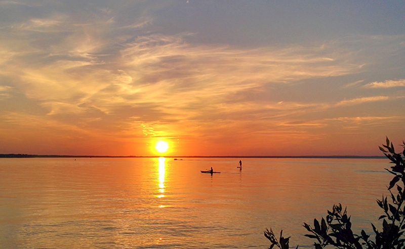 A paddleboarder and a kayaker on Clear Lake in Riding Mountain National Park in Manitoba at sunset. (Photo: Harry Wilson/Canadian Geographic)